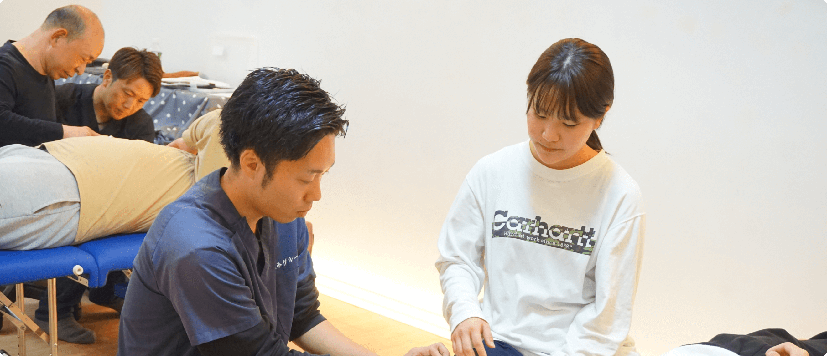 治療室で男性施術者が女性の手に触れながら、症状を確認しているようなシーン