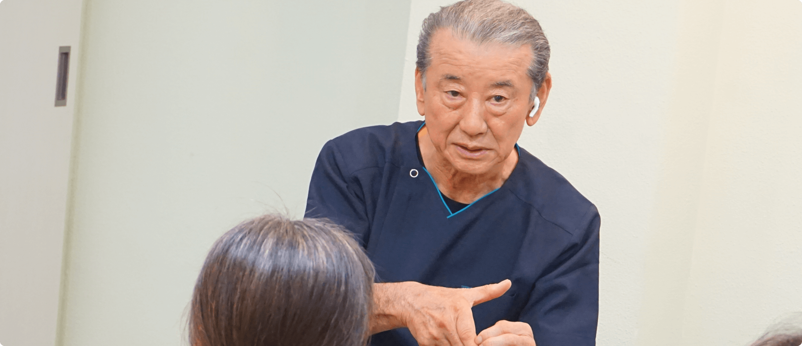 医療従事者と思われる男性が、椅子に座る女性に向けて説明や会話をしている場面