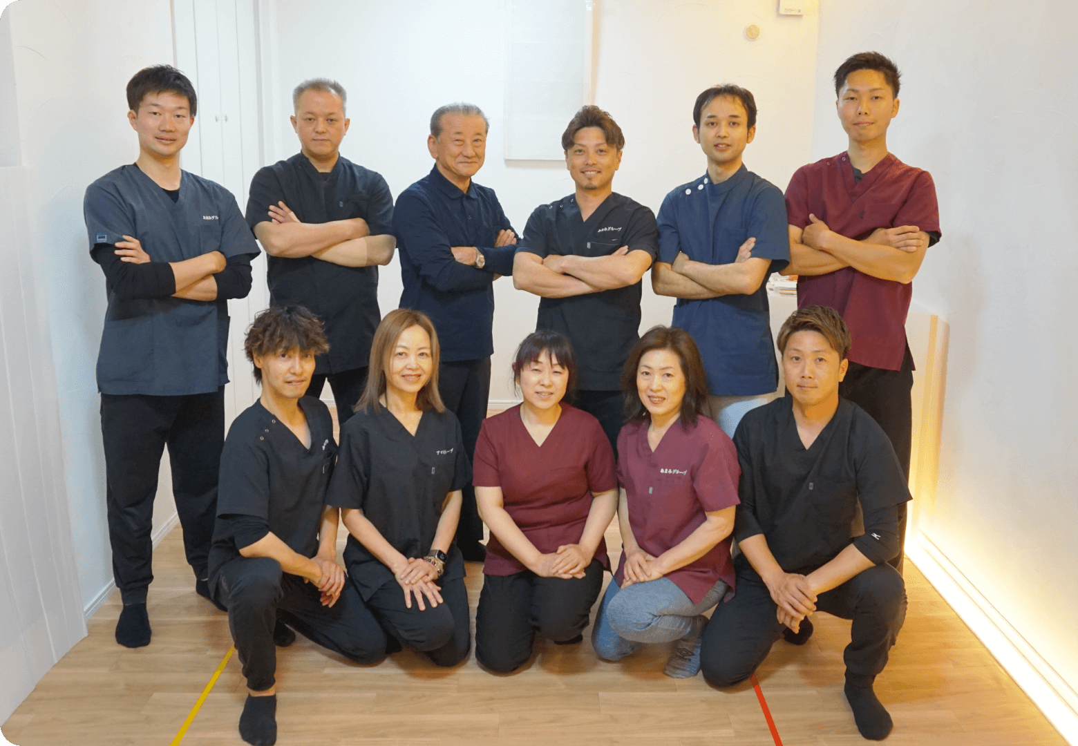 医療ユニフォーム姿の講師陣が笑顔で整列している集合写真