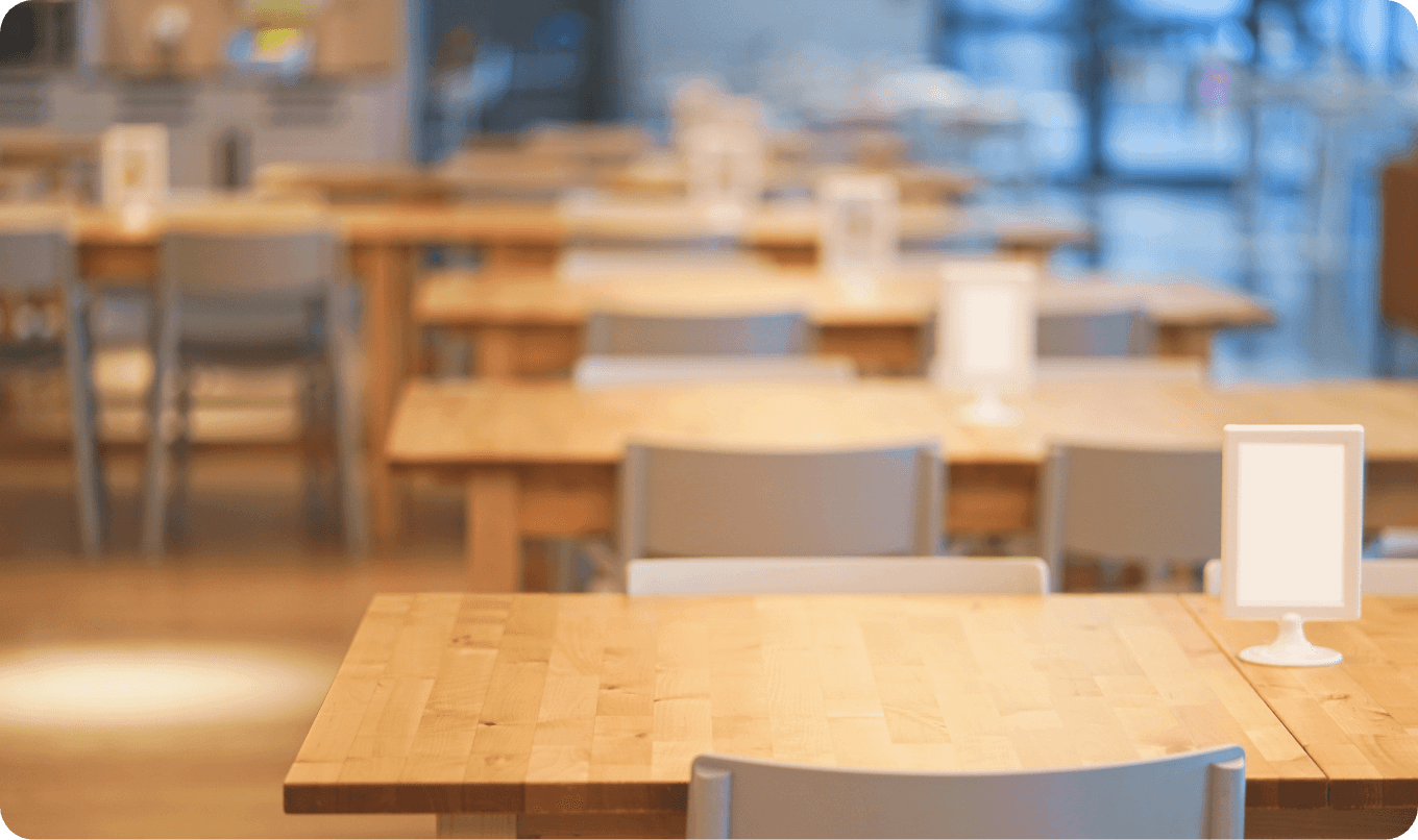 木製のテーブルと椅子が整然と並ぶ、明るく清潔感のあるカフェや食堂の店内風景。