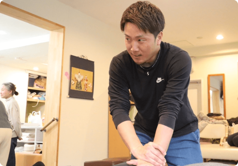 施術練習の様子。講師が実技のポイントを伝えながら受講者に指導している。